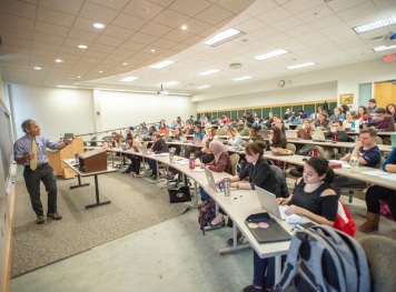 A professor holding a lecture in a classroom full of students.