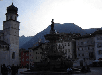 A picture of a fountain statue in the middle of a town center.