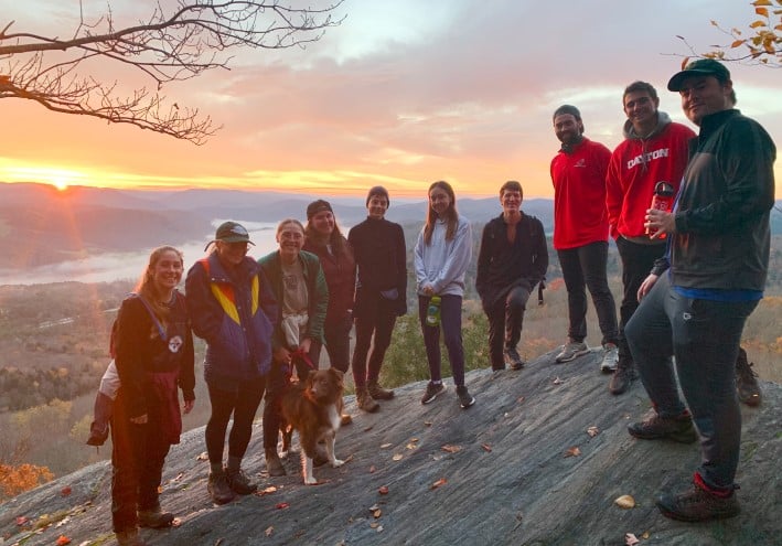Group of students and dog posing while on mountain hike.