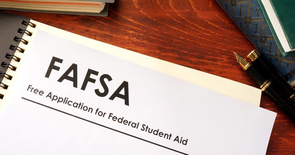 A desk with a pen. notebook, and document that says, "FAFSA: Free Application for Federal Student Aid"