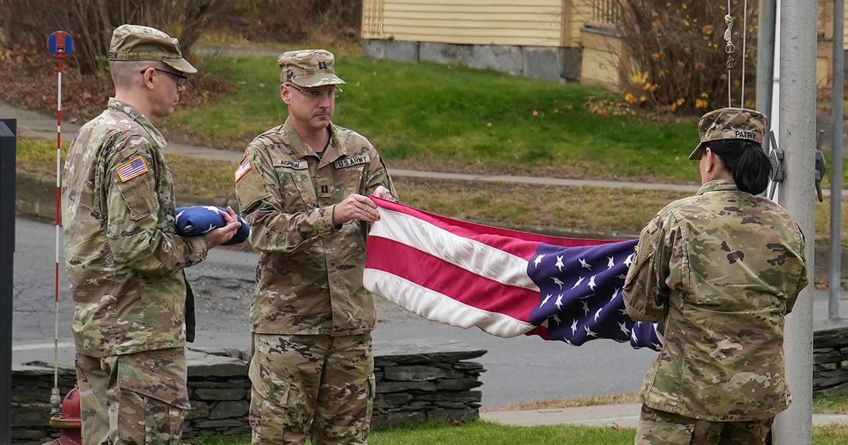 Military personnel fold the American flag.